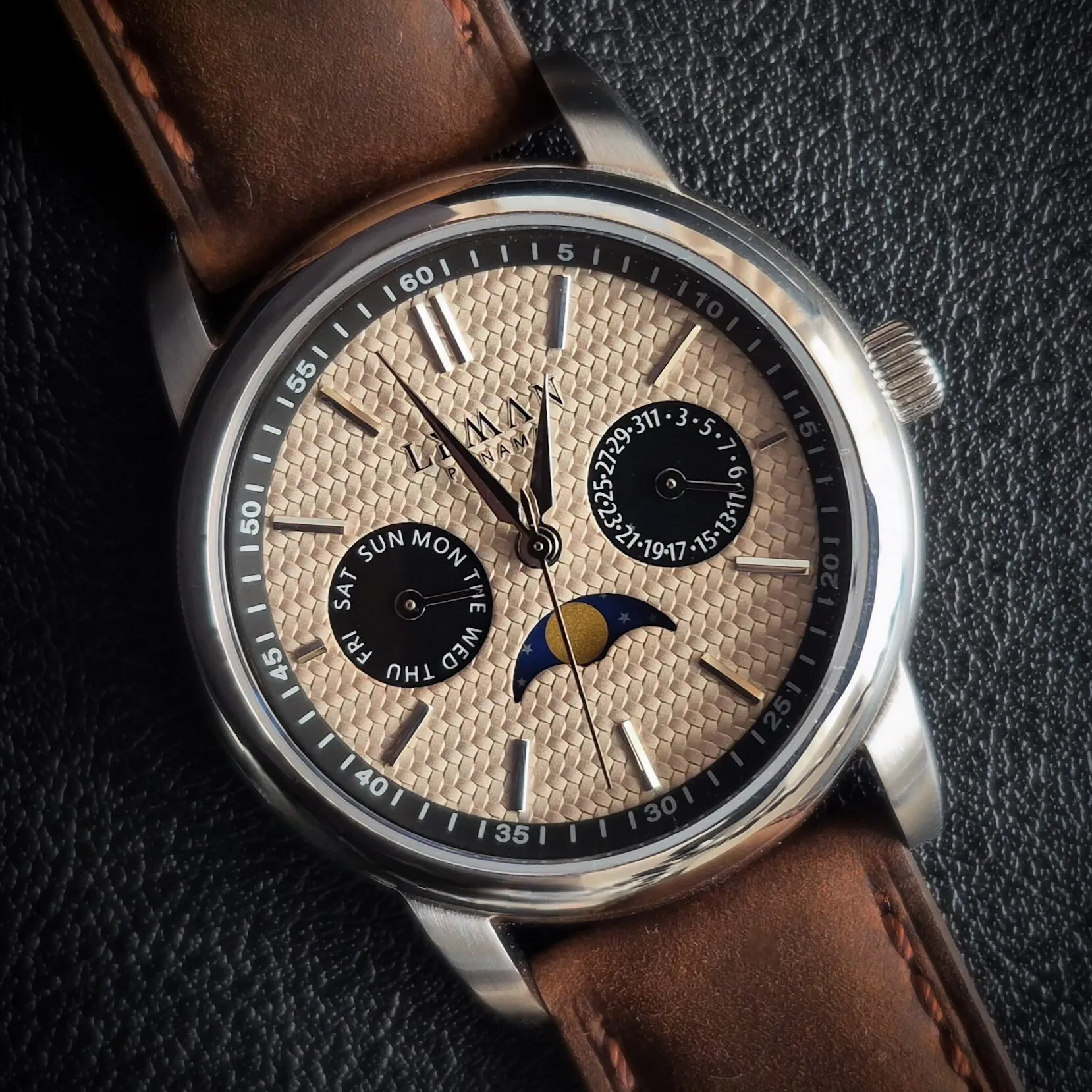 Leman Panama moonsphase watch close-up image against a black leather background featuring a brown leather strap