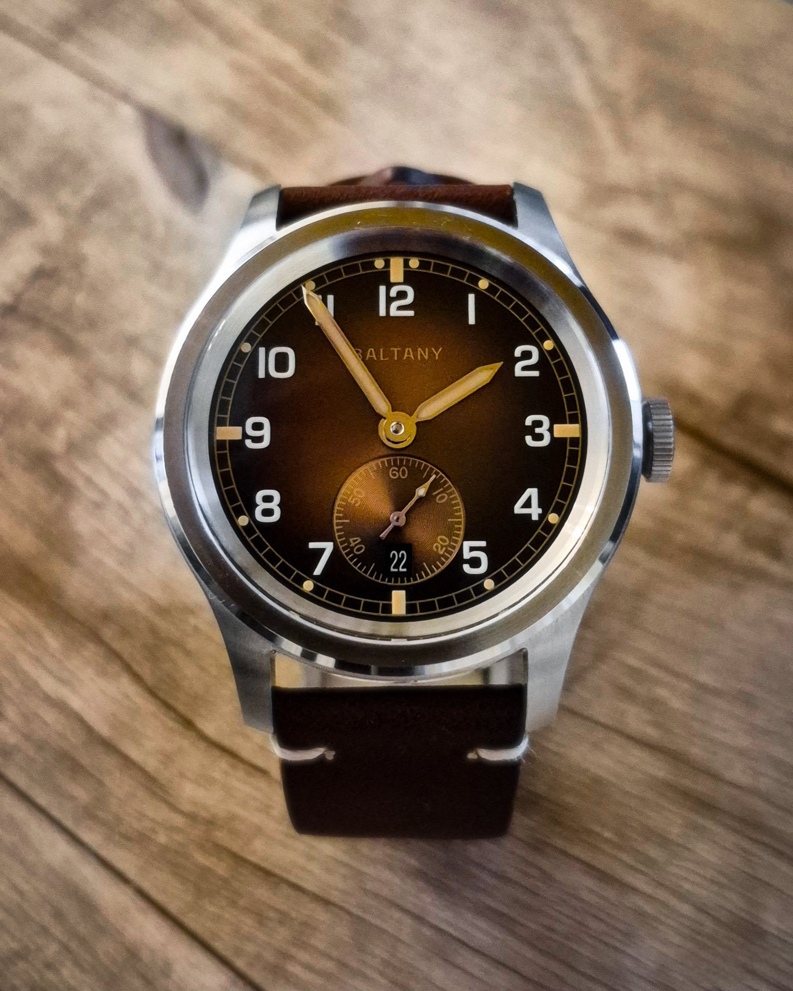 Baltany Dirty Dozen vintage watch close-up with visible dial and strap, placed on a rustic wooden background.