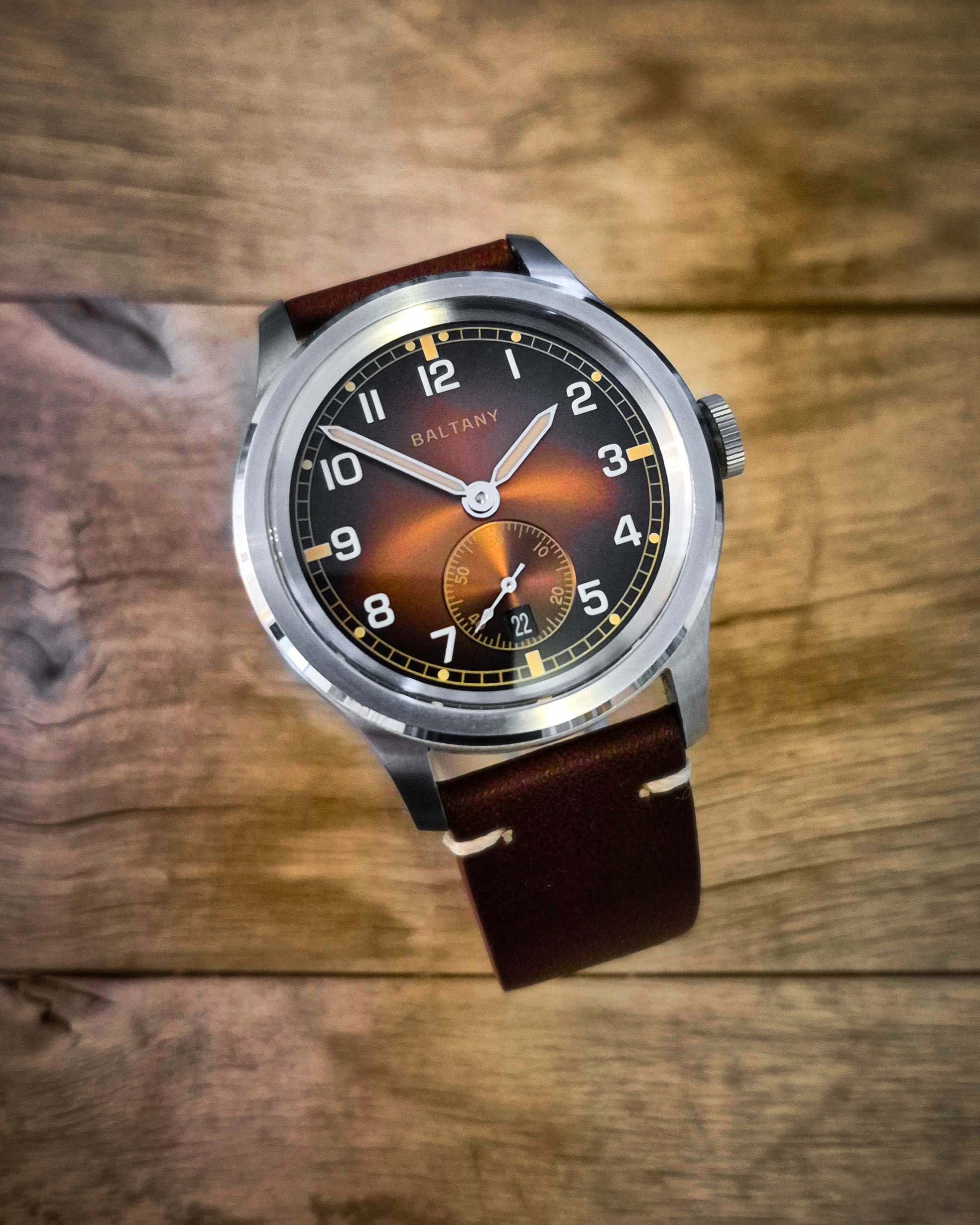 Baltany Dirty Dozen vintage watch close-up with visible dial and strap, placed on a rustic wooden background.